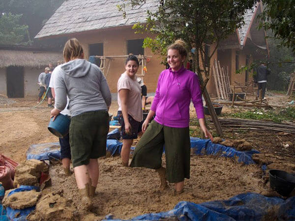 Ladies in makeshift cement mixer, mixing soil cement with feet