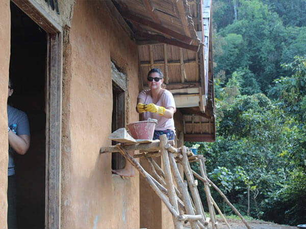 Lady wearing gloves and repairing home wall with soil compound